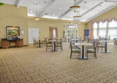 A second photo of the dining hall taken from a separate corner of the room. It includes views of the tables, chairs, exit, bank of windows. Included in this pic is a coffee bar station.