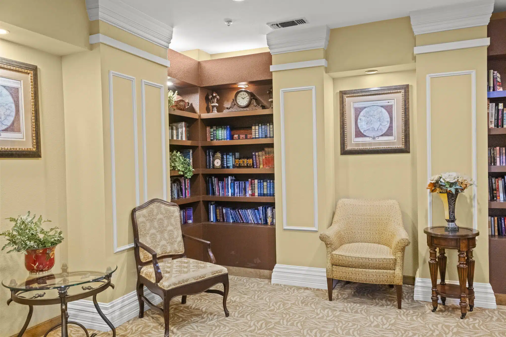Facility library/study with two floor-to-ceiling bookshelves and two chairs with decorative end tables.