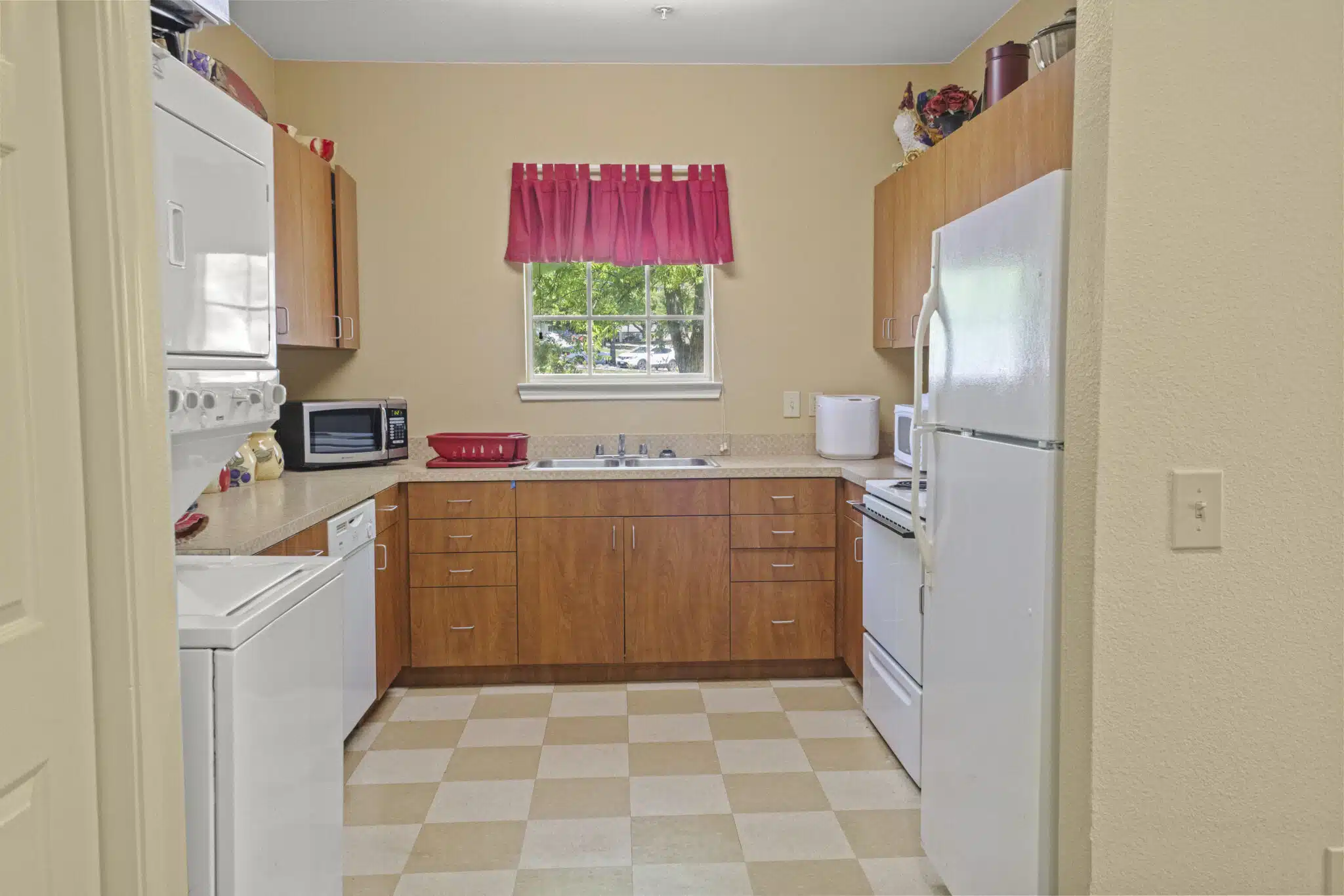 Photo of resident's kitchen with an L-shaped countertop. Appliances shown are Clothes washer and dryer, dishwashe, microwave oven, stove/oven, and refrigerator.