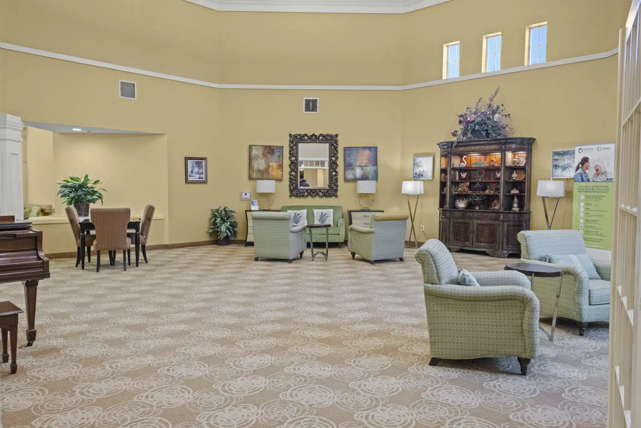 Spacious room with groups of chairs and tables arranged. A piano, hutch are also located in the room with artwork and a mirror on the walls.